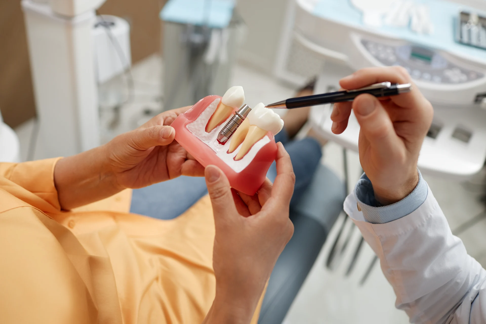 Dentist demonstrating a dental implant model to a patient in a clinic.